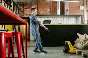 Un homme est dans un dépôt de stockage avec un appareil de manutention et de levage