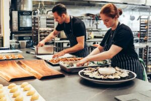 Un homme et une femme préparent une recette dans la cuisine d'un restaurant