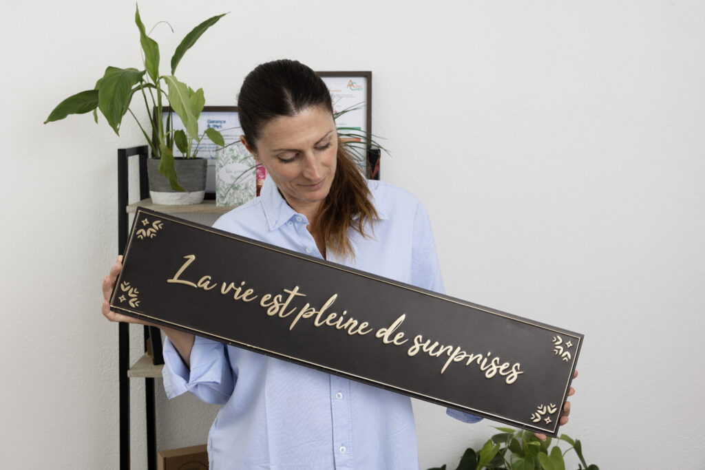 Muriel Molinier tenant une pancarte « La vie est pleine de surprises », cabinet de coaching professionnel à Castres